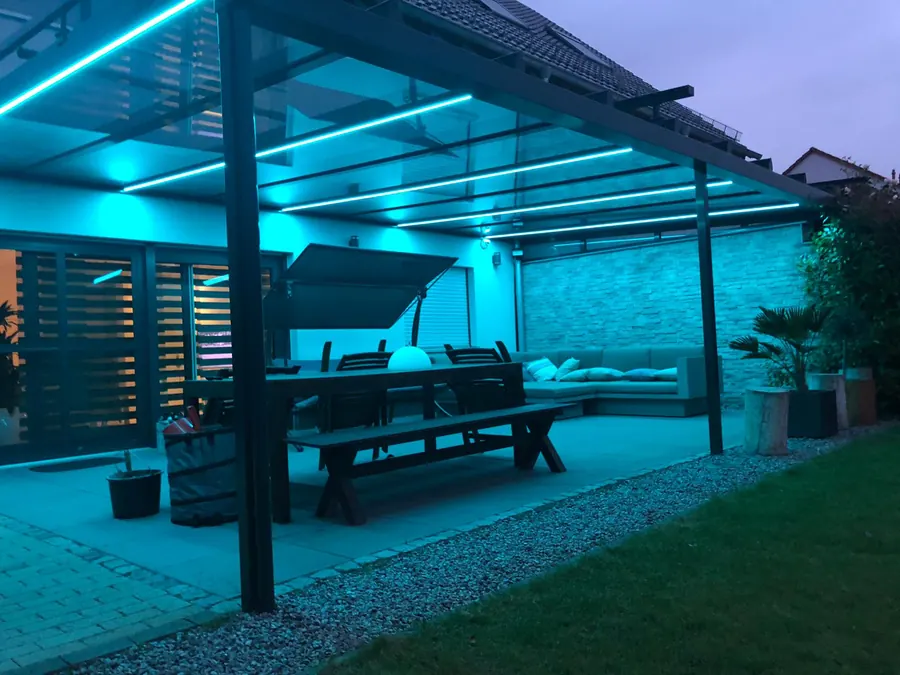 Terrassenüberdachung mit türkisfarbener Lichtlinie in der Dämmerung