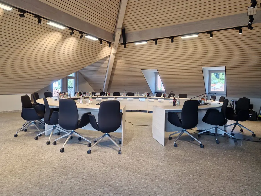 Konferenzraum unter Holzdachstuhl mit Stromschienenstrahlern