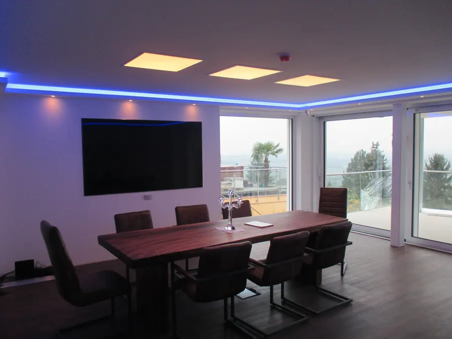 Besprechungsraum mit warmen LED-Panels und blauer Lichtvoute