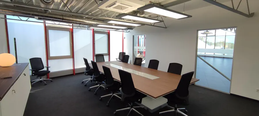 Langgestreckter Besprechungsraum mit abgependelten LED-Panels über dem Konferenztisch
